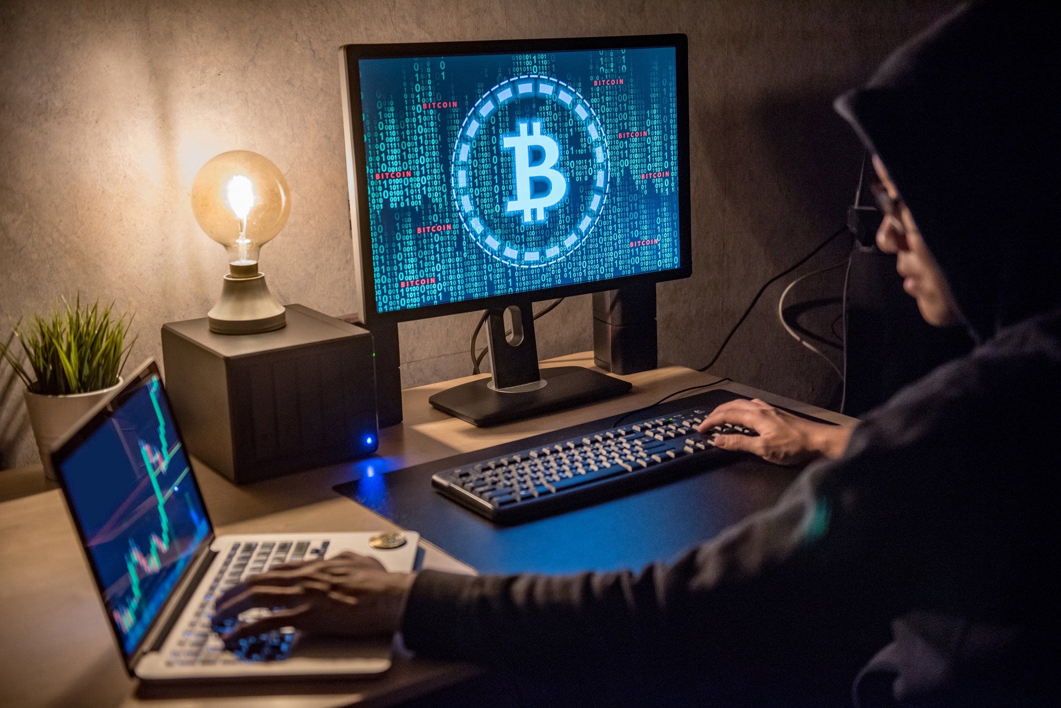 Cryptocurrency miner with chart on one monitor and Bitcoin symbol on another.